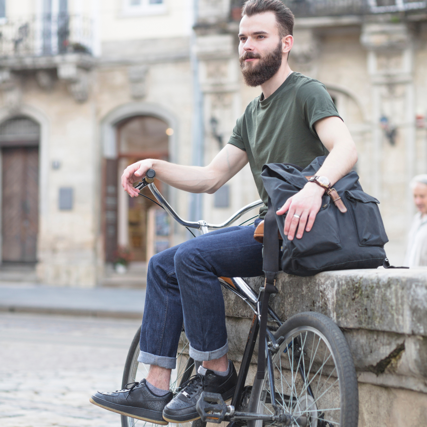 Fietser met laptop rugzak rust uit op stenen rand, praktische tas voor kortere trajecten in de stad