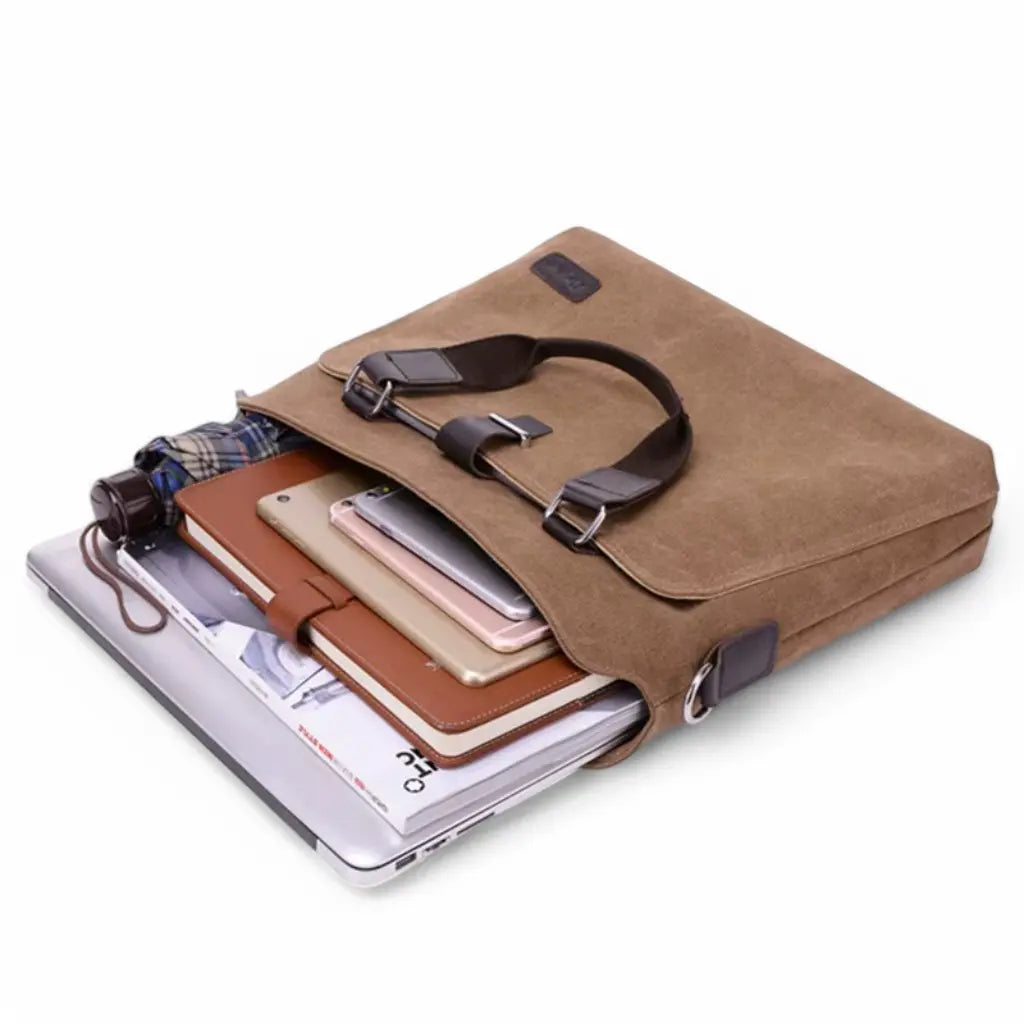 Canvas laptoptas heren met open binnenkant gevuld met laptop, boeken en andere benodigdheden, toont de ruime capaciteit.
