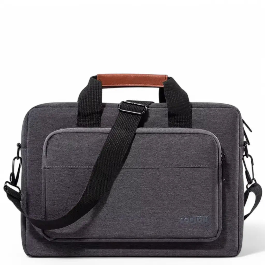 Stijlvolle design laptoptas heren donkergrijs met bruin lederen handgreep, zwarte schouderband en meerdere compartimenten. De COPTOT tas heeft een moderne uitstraling met een groot voorvak en is gemaakt van duurzaam textiel, ideaal voor dagelijks professioneel gebruik.