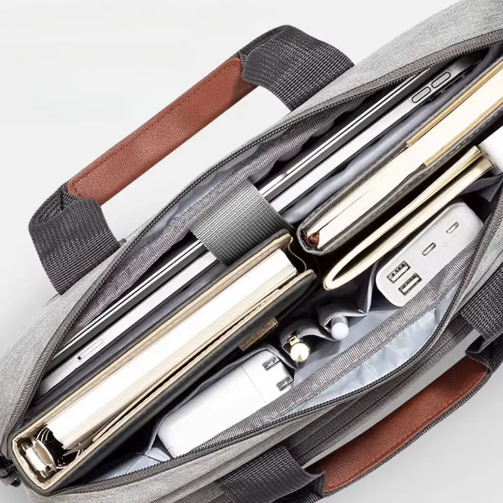 Bovenaanzicht van een geopende design laptoptas heren lichtgrijs gevuld met zakelijke essentials zoals laptop, notitieboeken, pennen en accessoires. De afbeelding toont de uitstekende organisatiemogelijkheden en ruimte van de COPTON tas.
