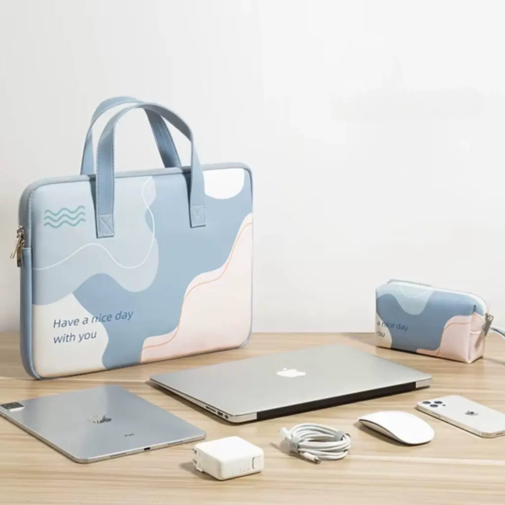 Complete set gekleurde laptoptas in lichtblauw met bijpassende accessoiretas, getoond naast een MacBook laptop en Apple apparaten. De stijlvolle beschermtas heeft een modern abstract design met de tekst "Have a nice day with you" en biedt ruime opbergmogelijkheden.