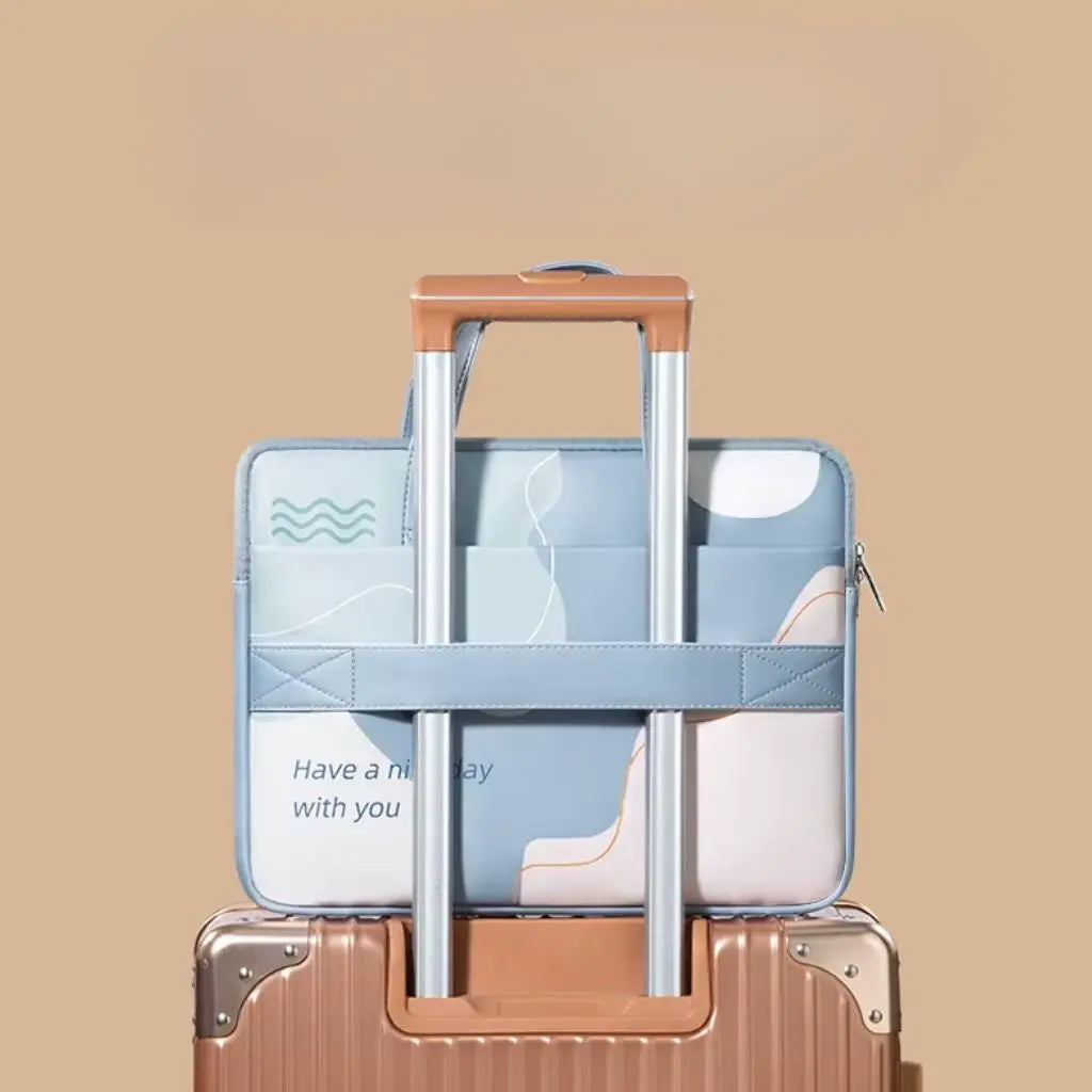 Gekleurde laptoptas met abstract design bevestigd aan trolleykoffer via de achterzijde. De lichtblauwe tas met "Have a nice day with you" tekst heeft een speciaal ontworpen band voor bevestiging aan rolkoffers, ideaal voor op reis.
