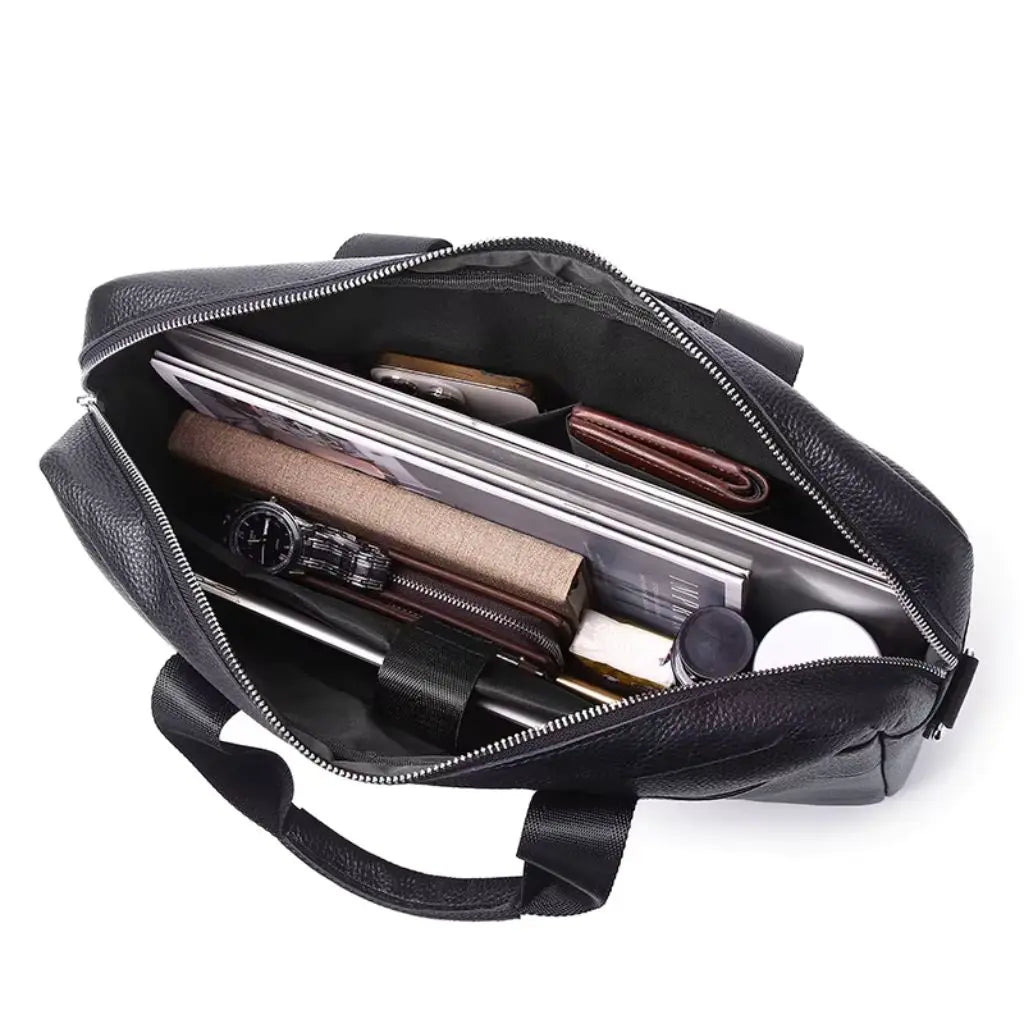 Binnenaanzicht van de leren laptoptas heren zwart gevuld met laptop, documenten, portemonnee en accessoires. De ruime tas biedt voldoende opbergruimte met meerdere compartimenten en een gevoerde bescherming voor elektronische apparaten.
