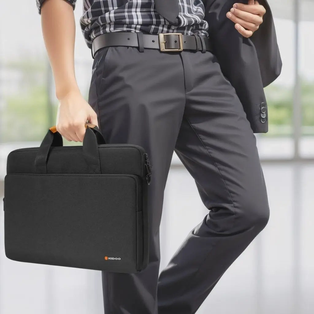 Een zakenman draagt een bijzondere laptoptas heren 17 inch met zwart design en handige draaghengsels, perfect passend bij een formele outfit met geruite blouse en nette broek.