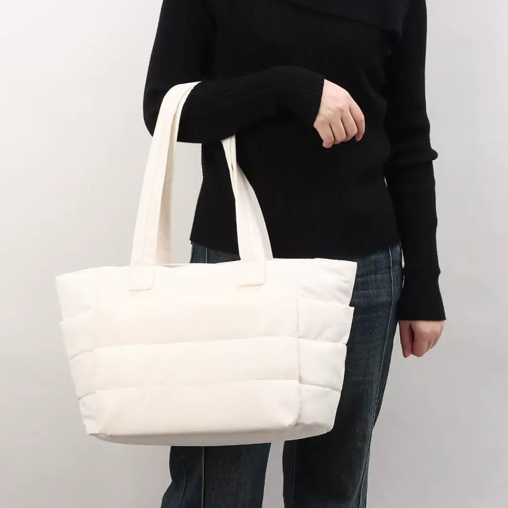 Witte variant van de coole laptoptas dames 15.6 inch gedragen door een vrouw in zwarte kleding, elegante combinatie voor dagelijks gebruik.