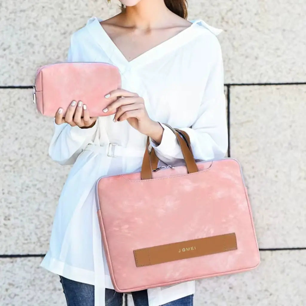 Een vrouw in witte blouse draagt een elegante laptoptas dames 16 inch roze met bruine handvatten en houdt het bijpassende accessoiretasje vast.