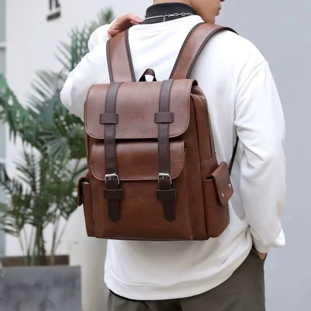 Een man draagt de Heren laptop rugzak 13 inch bruin op de rug. De bruine rugzak heeft een vintage design met lederen gespen en verstelbare schouderbanden.
