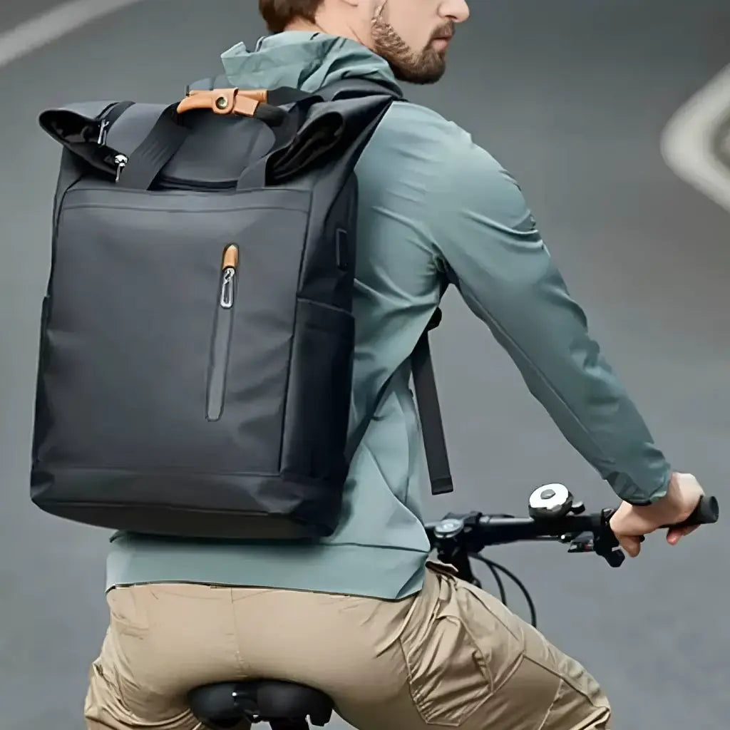 Laptop rugzak 15.6 inch fiets gedragen door een fietser in een mintgroen shirt, de zwarte rugzak biedt optimaal draagcomfort tijdens het fietsen door Nederlandse steden met ergonomische schouderriemen en gebalanceerde gewichtsverdeling.
