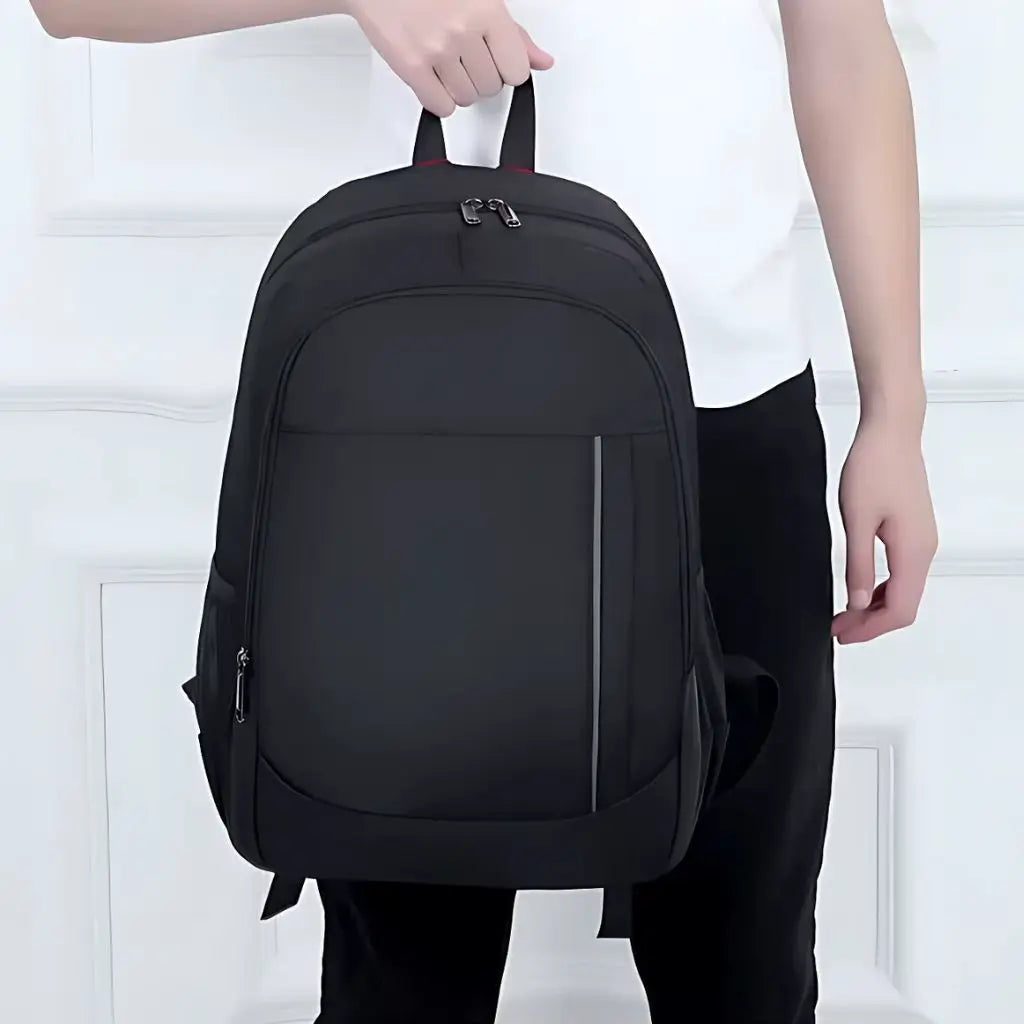 Man houdt een zwarte laptop rugzak 17.3 inch vast aan het handvat. Het ontwerp is minimalistisch en ideaal voor school of dagelijks gebruik.