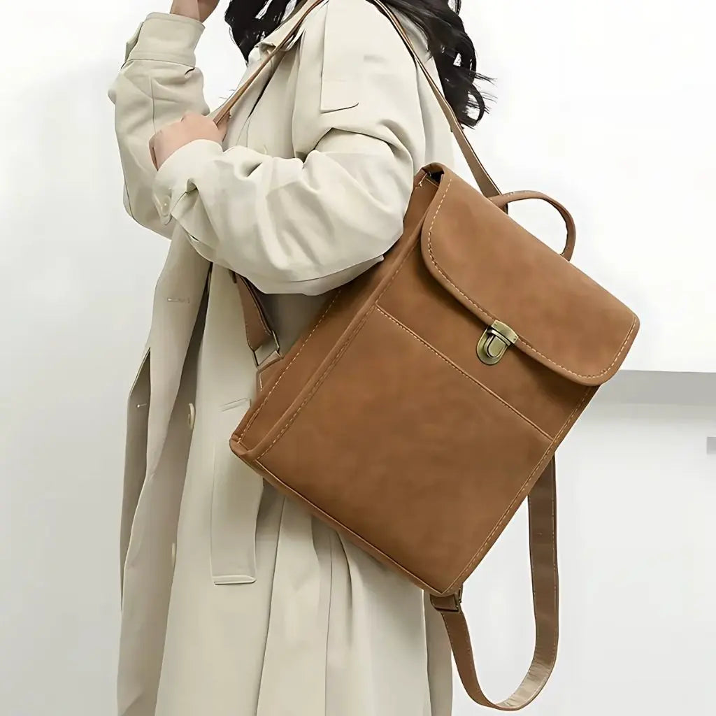 Laptop rugzak dames 13 inch gedragen door een vrouw in een beige jas. De rugzak wordt over de schouder gedragen, wat een elegante en trendy look geeft.