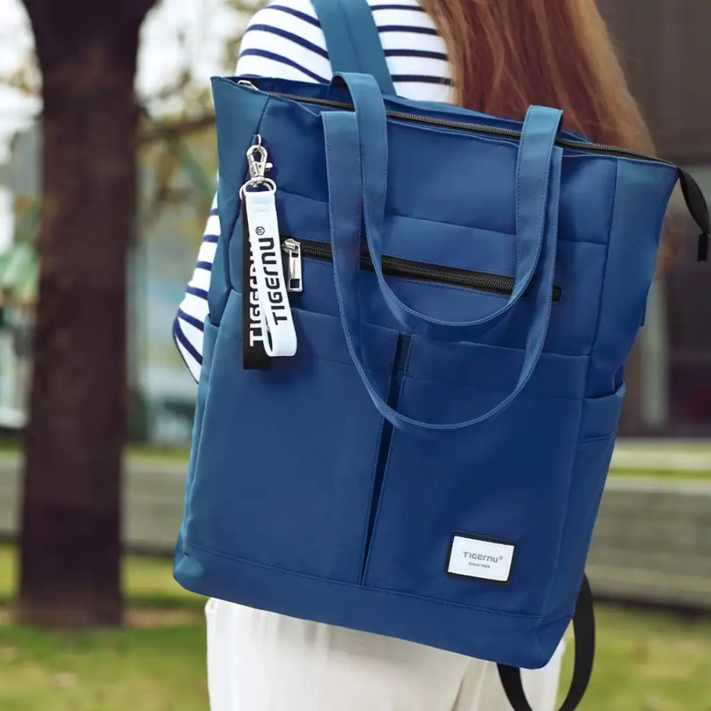 Vrouw draagt een laptop rugzak dames 15.6 inch blauw als handtas, praktisch en elegant voor dagelijks gebruik.