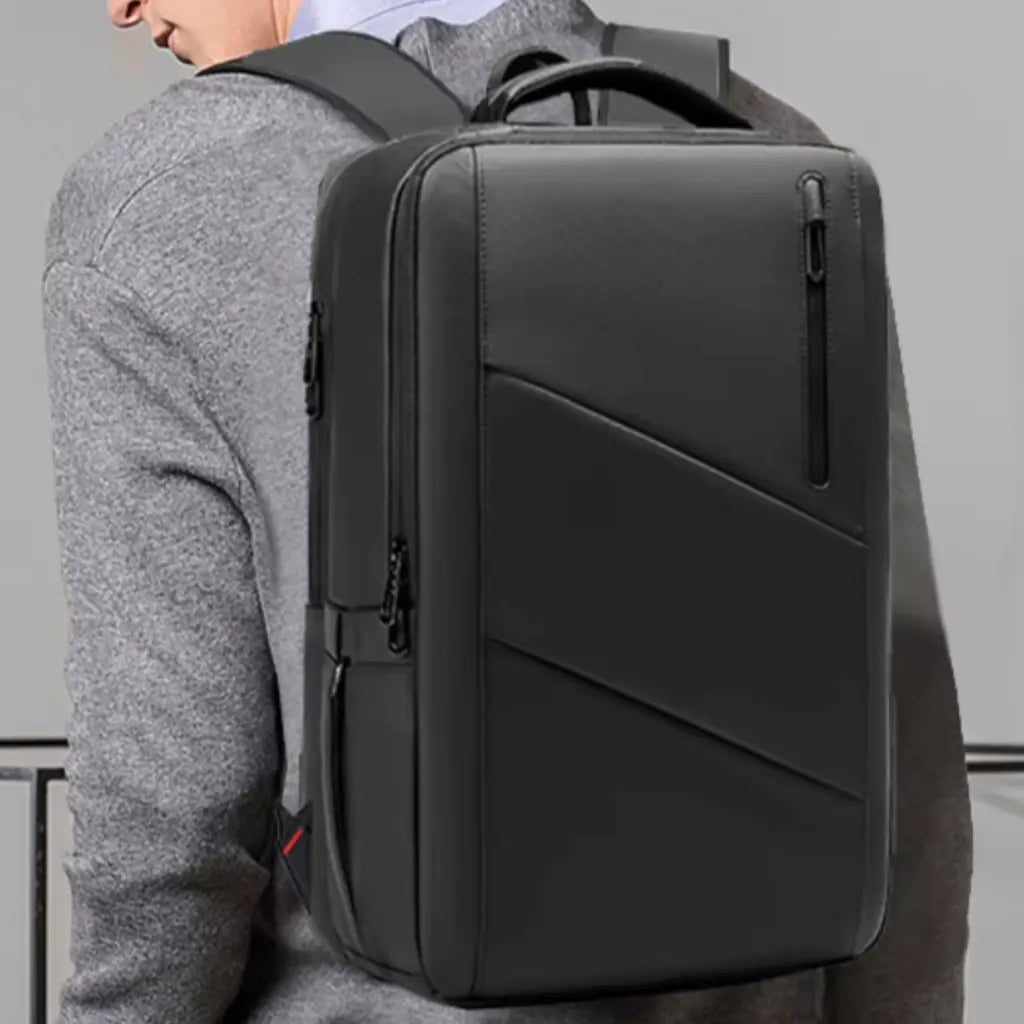 Een model draagt een laptop rugzak heren 15 inch, wat het draagcomfort en de pasvorm demonstreert. De rugzak heeft een ergonomisch ontwerp dat comfortabel op de rug zit, zelfs bij langdurig gebruik. Het strakke zwarte design met de diagonale lijnen combineert een professionele uitstraling met praktisch gemak voor dagelijks gebruik.