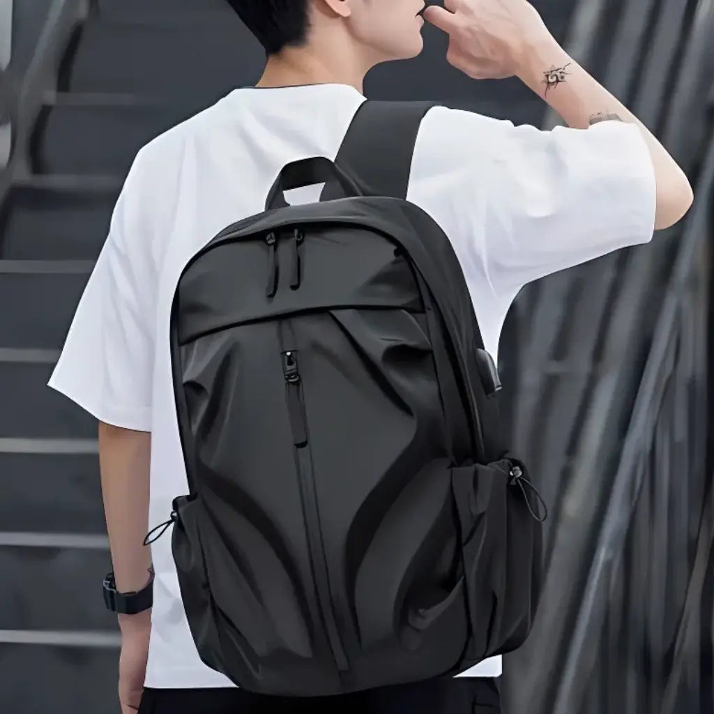 Jonge man in wit shirt met een zwarte laptop rugzak heren 17 inch op zijn rug, toont het draagcomfort en de stijlvolle pasvorm van deze moderne laptop rugzak heren 17 inch tijdens een dagelijkse pendel.