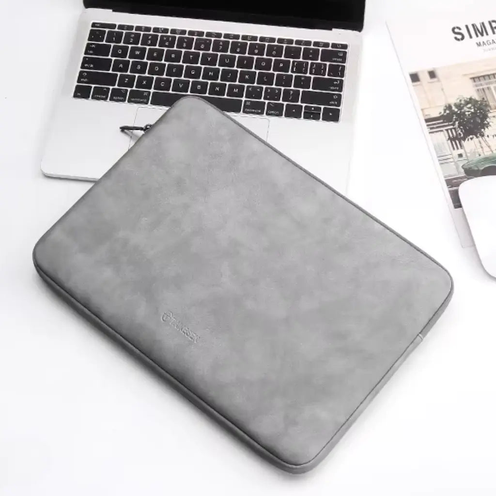 Grijze laptop sleeve 14 inch liggend op een MacBook, perfect passend voor moderne laptops