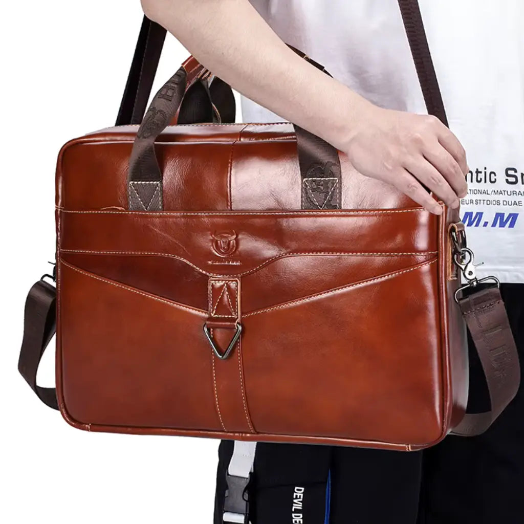 Man in wit shirt draagt laptoptas cognac heren 15 inch aan de schouderband, perfect voor zakelijk gebruik.
