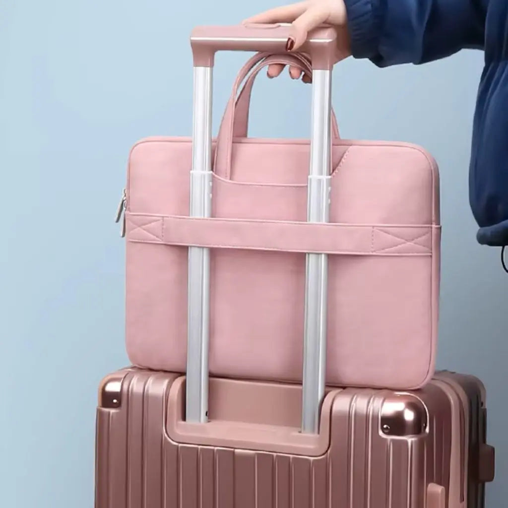 Laptoptas dames klein roze bevestigd aan een roségouden rolkoffer. De speciaal ontworpen band aan de achterkant maakt het mogelijk de tas gemakkelijk over de handgreep van een koffer te schuiven, ideaal voor reizende professionals.