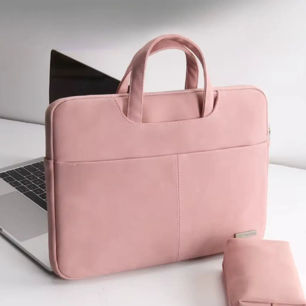 Laptoptas dames klein roze naast een laptop op een witte bureau-achtergrond. Het elegante, minimalistische design en de zachte rozetint maken deze tas een modieus accessoire voor professionele vrouwen die waarde hechten aan stijl en functionaliteit.