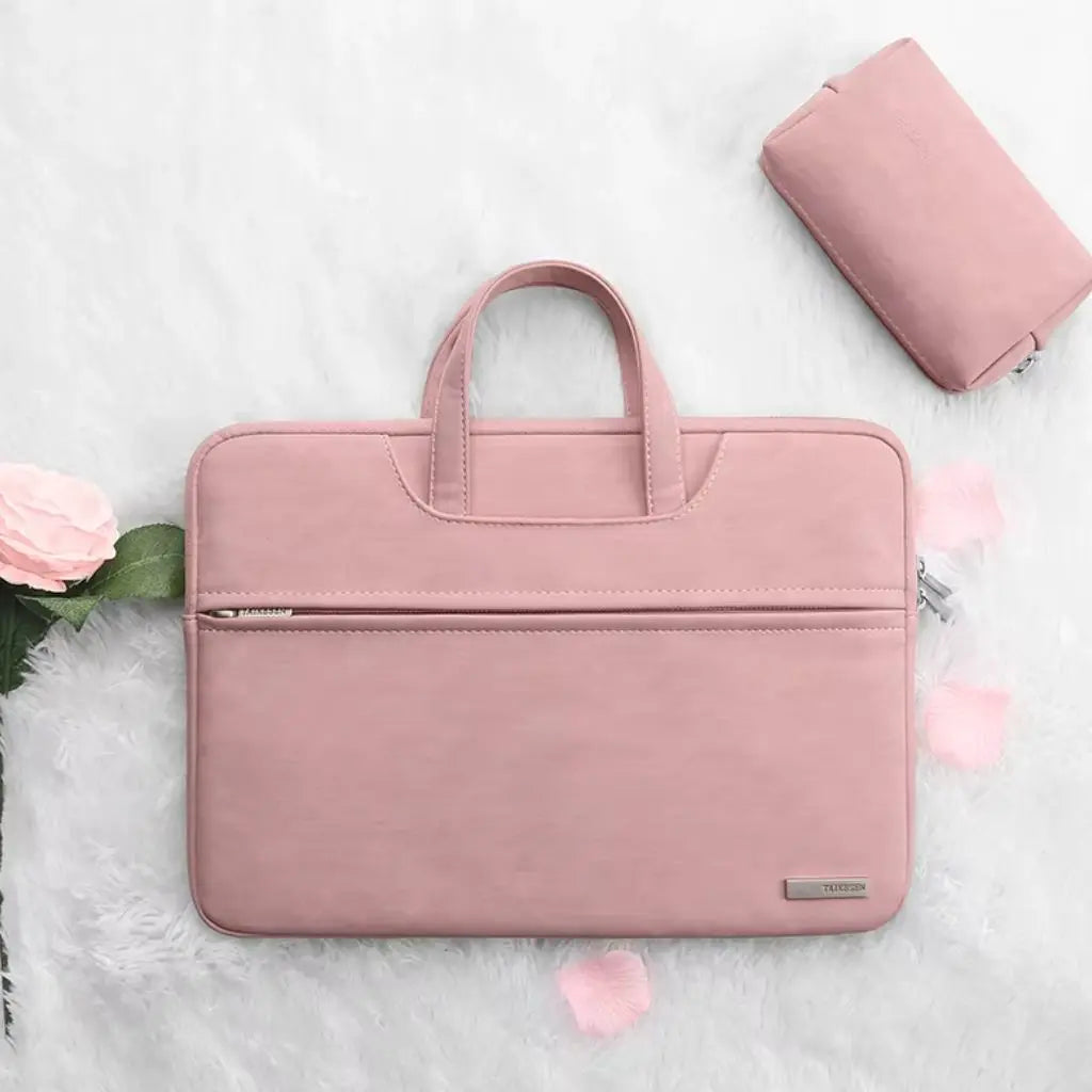 Laptoptas dames klein roze gepresenteerd op een zachte witte ondergrond met roze bloemblaadjes en een bijpassende accessoire-tas. Het elegante roze design met TAIKESEN-label vormt een stijlvolle combinatie voor vrouwen die functionaliteit en mode waarderen.