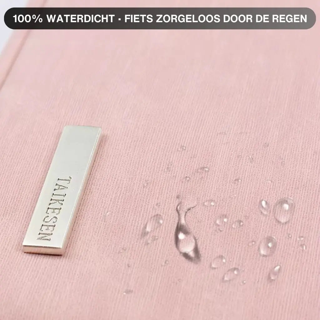 Close-up van de waterdichte laptoptas dames klein roze met waterdruppels op het oppervlak. De tekst "100% WATERDICHT - FIETS ZORGELOOS DOOR DE REGEN" benadrukt de bescherming die deze tas biedt, perfect voor Nederlandse weersomstandigheden.