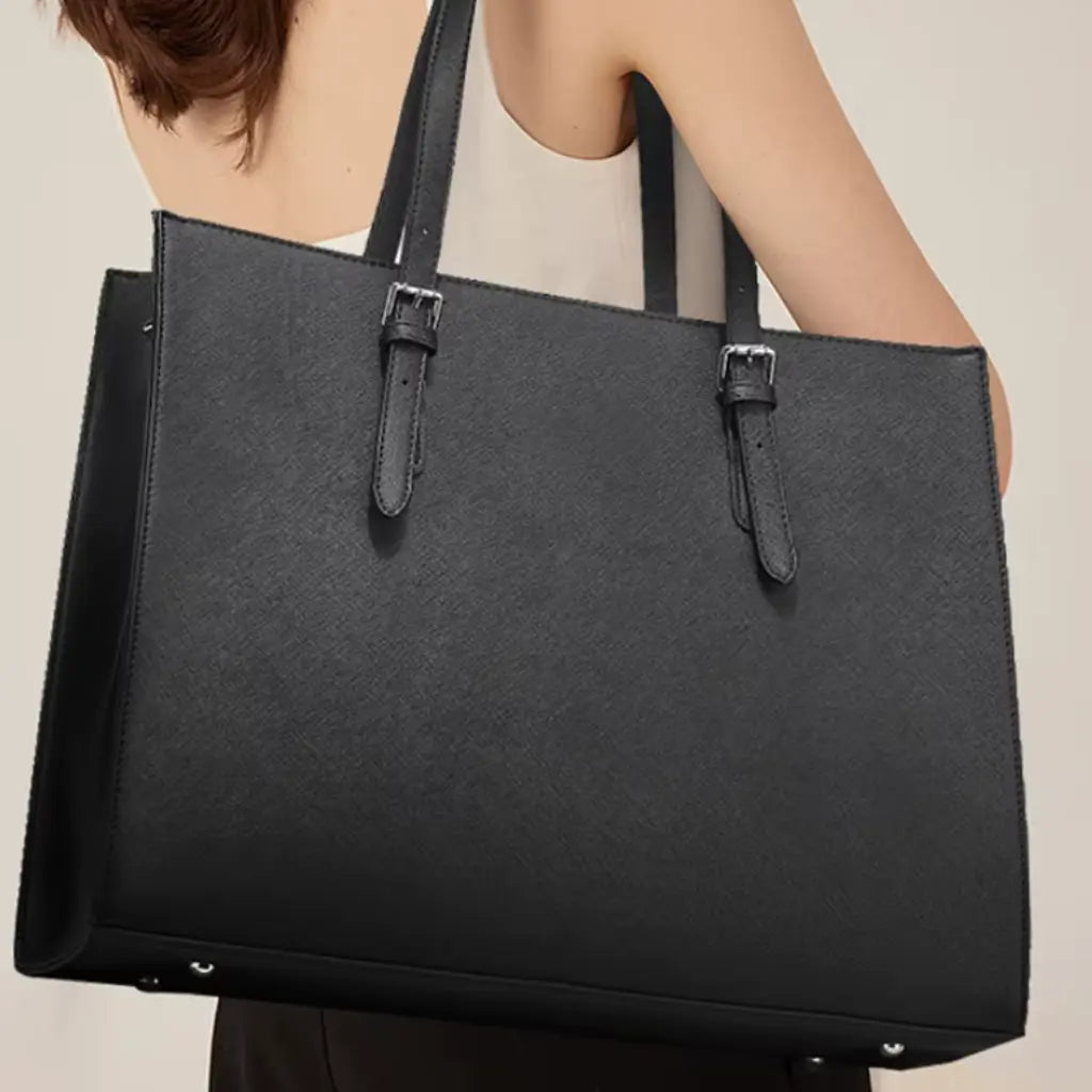 Elegante zwarte laptoptas shopper 15.6 inch gedragen door een vrouw, met verstelbare schouderriemen en moderne vormgeving.
