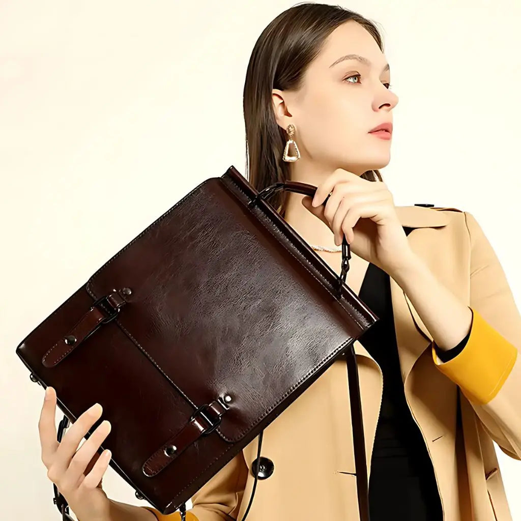 Vrouw houdt een leren laptop rugzak 13 inch vast bij het handvat, met een gestructureerd ontwerp en elegante metalen gespen.