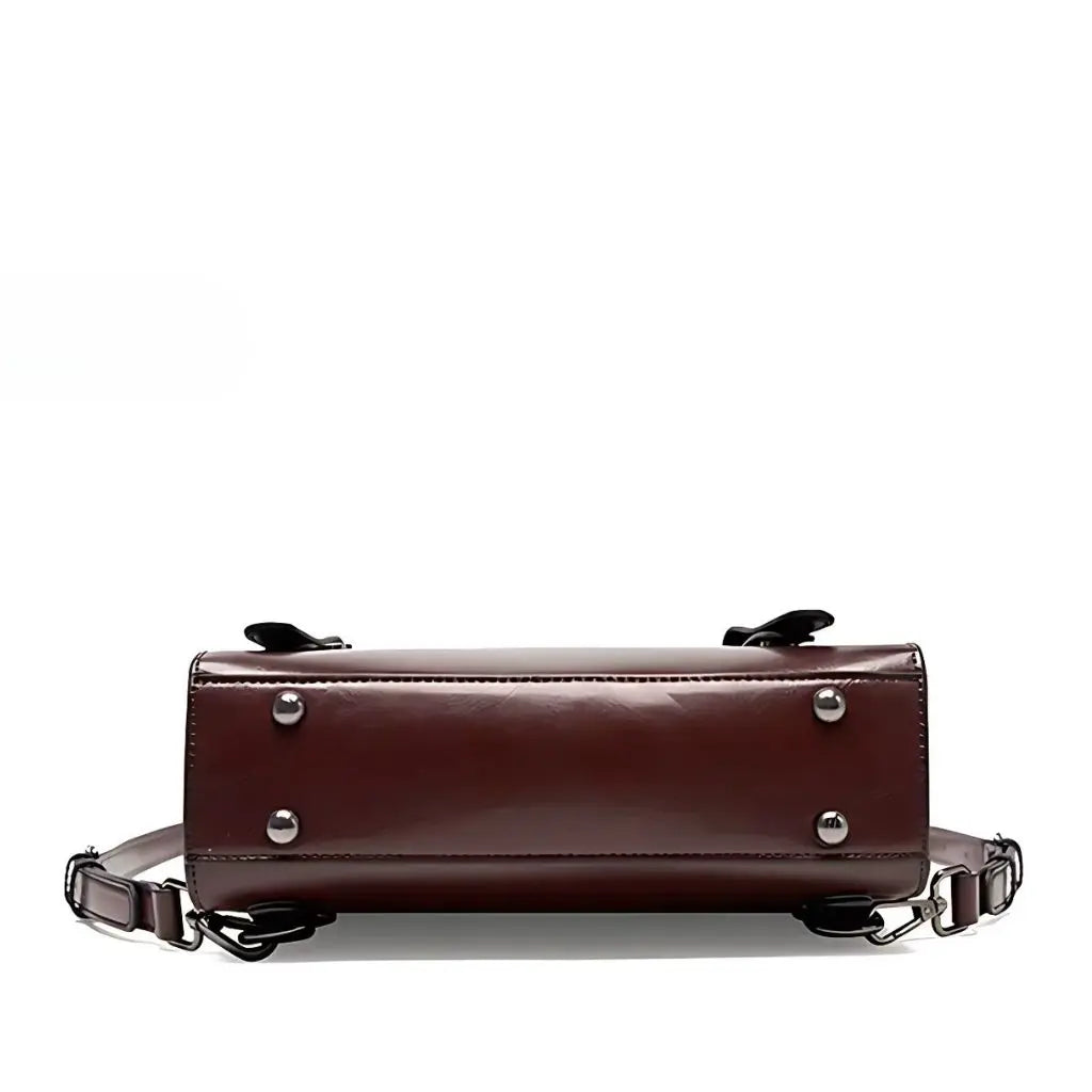 Onderkant van een leren laptop rugzak 13 inch, voorzien van vier metalen beschermknoppen voor stabiliteit en extra duurzaamheid.