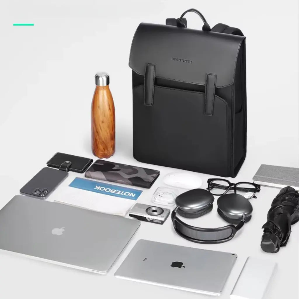 Flatlay-foto van een zwarte leren laptop rugzak 15.6 inch naast essentiële dagelijkse items zoals laptop, hoofdtelefoon, waterfles en accessoires, illustreert de capaciteit en veelzijdigheid van deze premium leren laptop rugzak 15.6 inch.