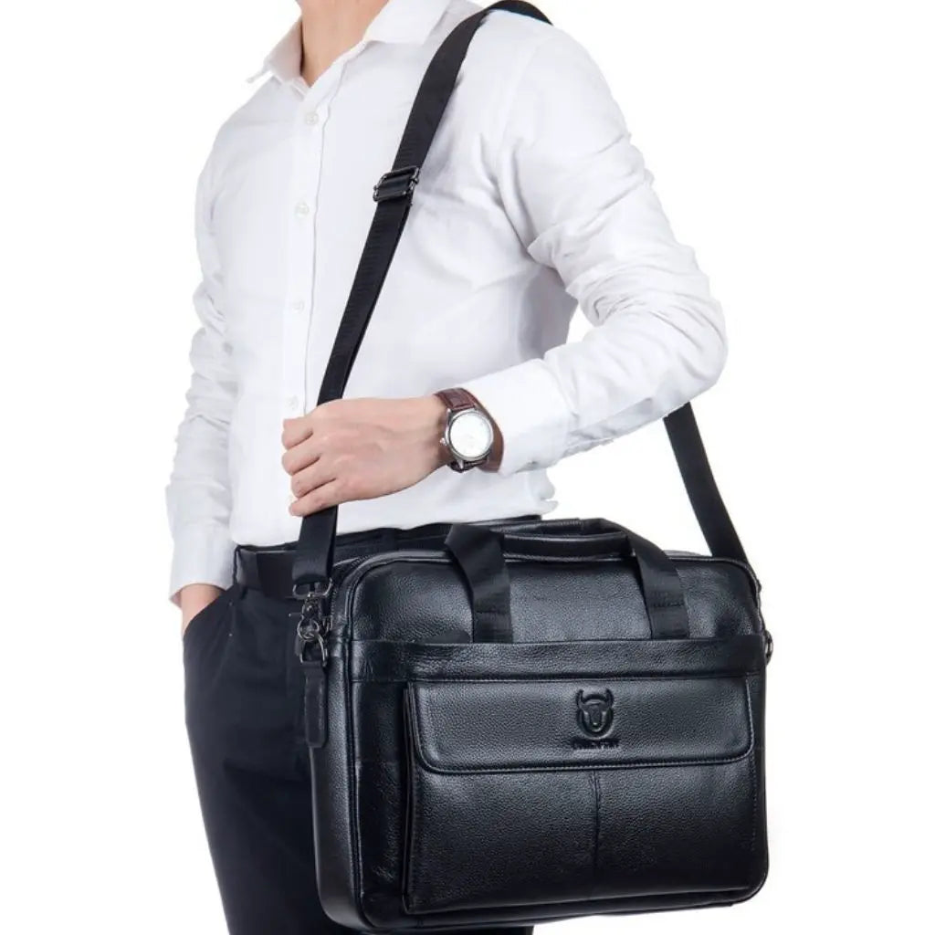 Leren laptoptas heren 16 inch zwart gedragen aan de schouderband door een man in formele kleding, demonstreert het gebruiksgemak en stijlvolle design voor moderne Nederlandse professionals.