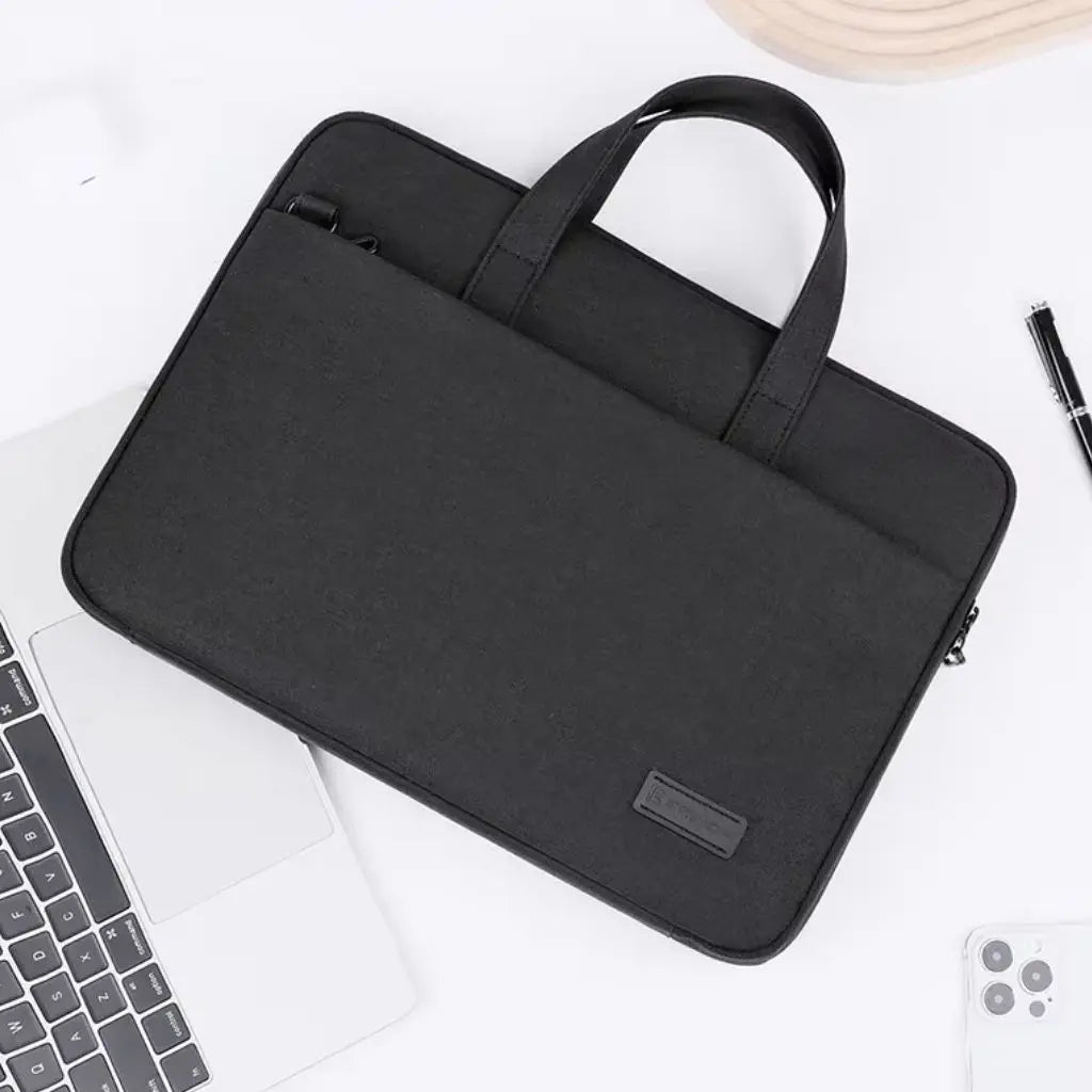 Een lichte laptoptas dames 17 inch zwart op een minimalistische werkplek naast een laptop en pen, illustreert de stijlvolle en functionele aard van de tas voor dagelijks gebruik.