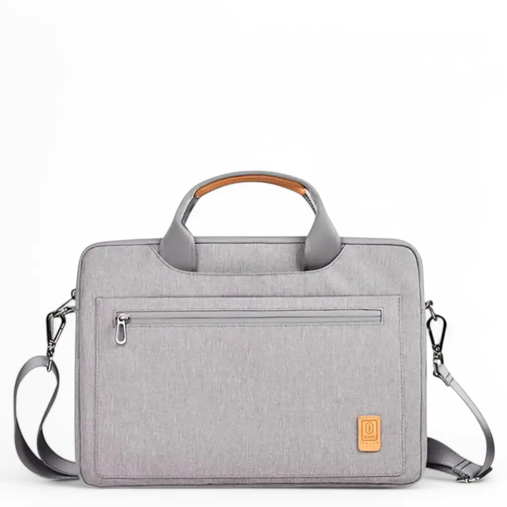Stijlvolle laptoptas dames 16 inch grijs gemaakt van hoogwaardig textiel met oranje accent op de handgreep, ritssluiting aan de bovenkant en een voorvak met rits op een witte achtergrond.