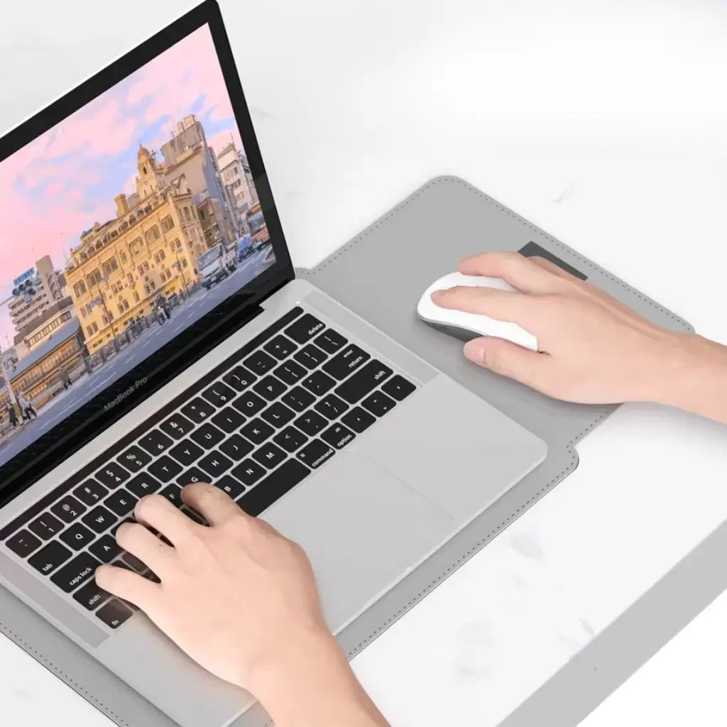 Leren laptop hoes met MacBook in gebruik, toont praktische muismat functie voor optimale werkplek onderweg.