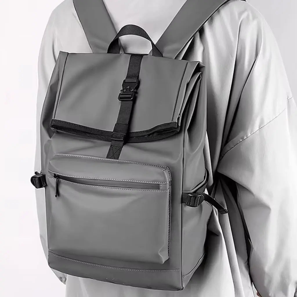 Een nette laptop rugzak heren 13 inch Grijs, gedragen op de rug door een man in een lichte jas. De rugzak heeft verstelbare banden en een waterdicht ontwerp.
