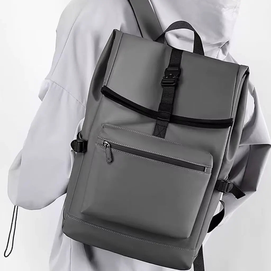 Een nette laptop rugzak heren 13 inch Grijs, gedragen schuin over de schouder. De grijze rugzak heeft een modern design en een stevige gesp.