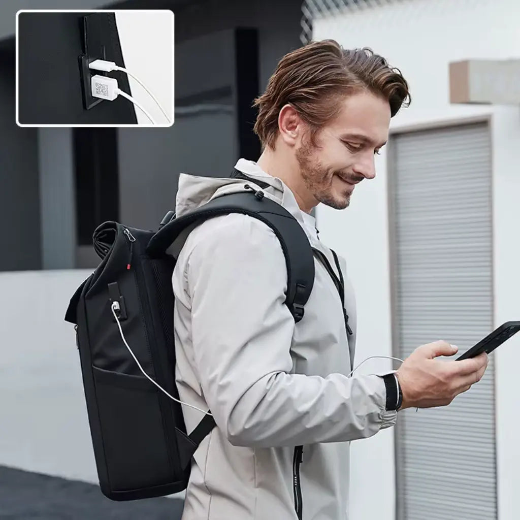 Man met Nomad laptop rugzak met ingebouwde USB-oplaadpoort, waarmee mobiele telefoon wordt opgeladen tijdens het lopen.