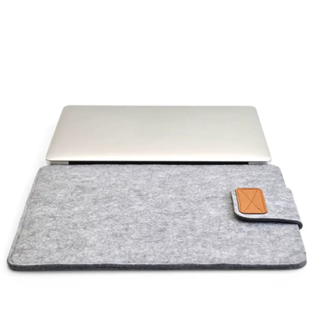 Leuke laptop hoes in grijs vilt met MacBook, toont perfecte pasvorm en subtiel leren accent.