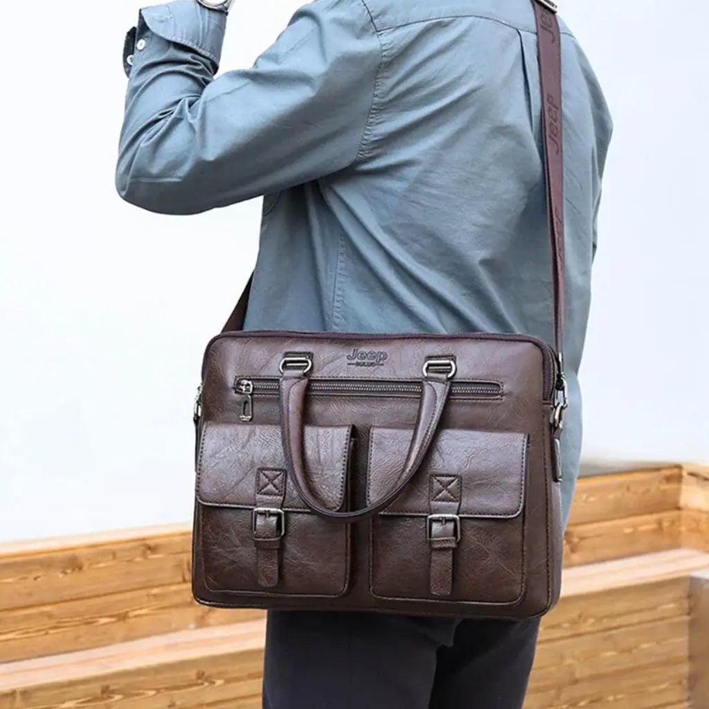 Man in blauwe jas draagt een leren laptoptas heren 13 inch bruin donkerbruin met schouderriem, toont de praktische draagwijze van de Jeep business tas voor dagelijks gebruik.