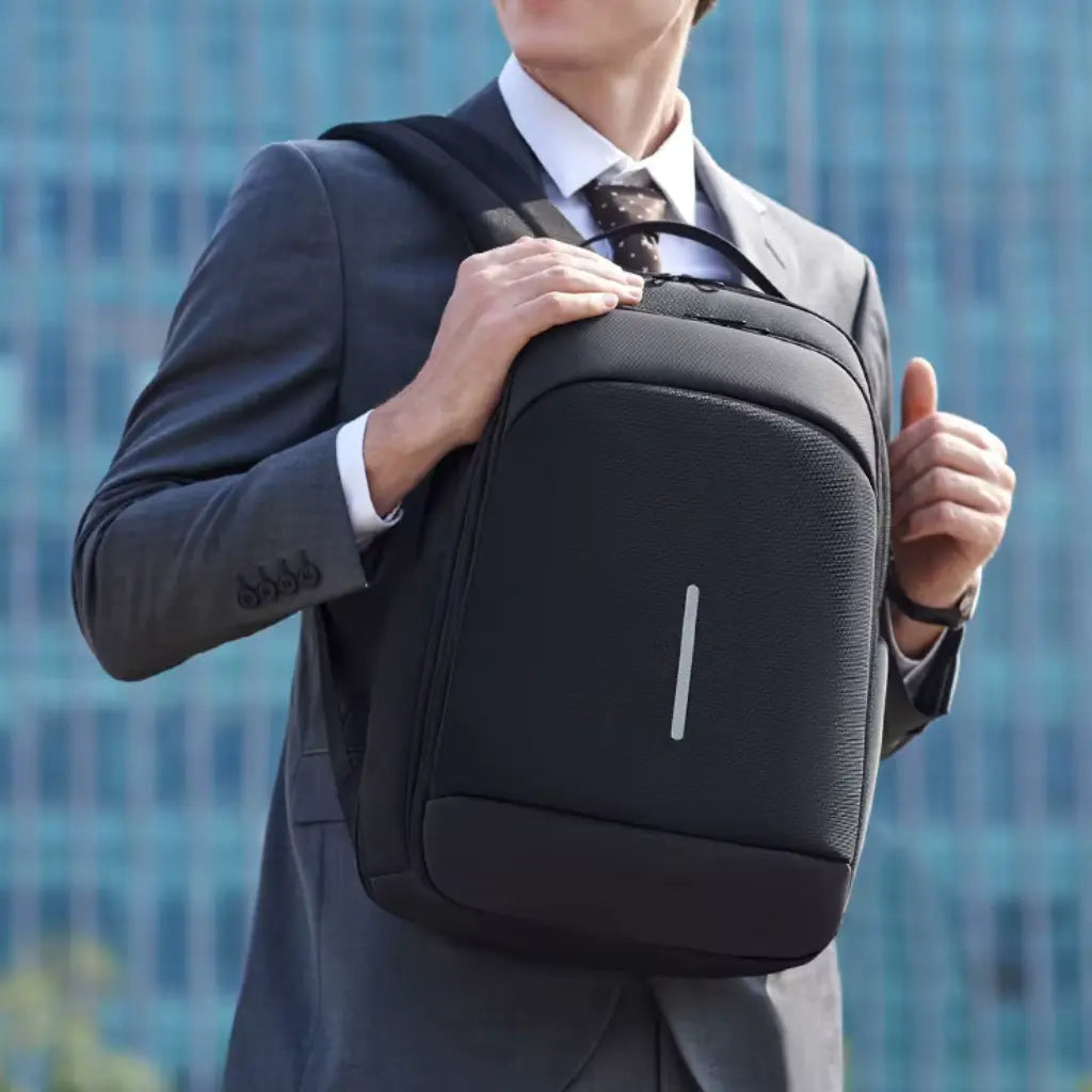 Jonge zakenman met zonnebril draagt waterdichte laptop rugzak school 16 inch gecombineerd met een formeel pak voor een moderne professionele uitstraling.