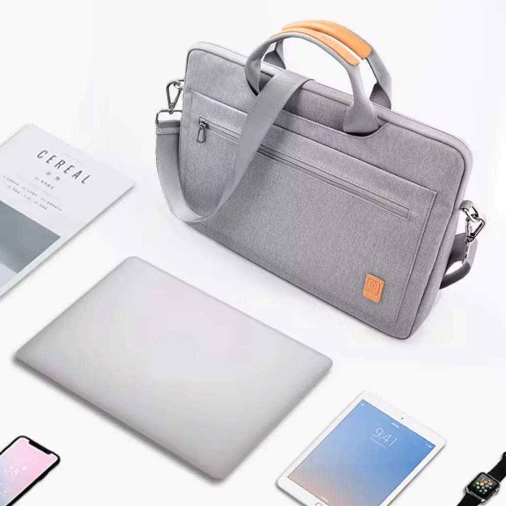 Laptoptas dames 16 inch grijs getoond in een professionele werkomgeving naast een laptop, tablet, smartphone en tijdschrift, perfect voor zakelijk gebruik.