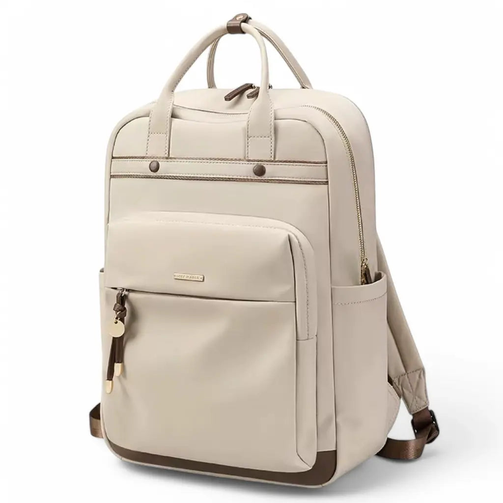 Een frontale weergave van een waterdichte laptop rugzak 15.6 inch beige met bruine accenten. De rugzak heeft een mooi gedetailleerd ontwerp met metalen knoppen, meerdere compartimenten en een voorvak met rits en decoratieve hangers. De combinatie van beige en bruin geeft de tas een tijdloze, professionele uitstraling.