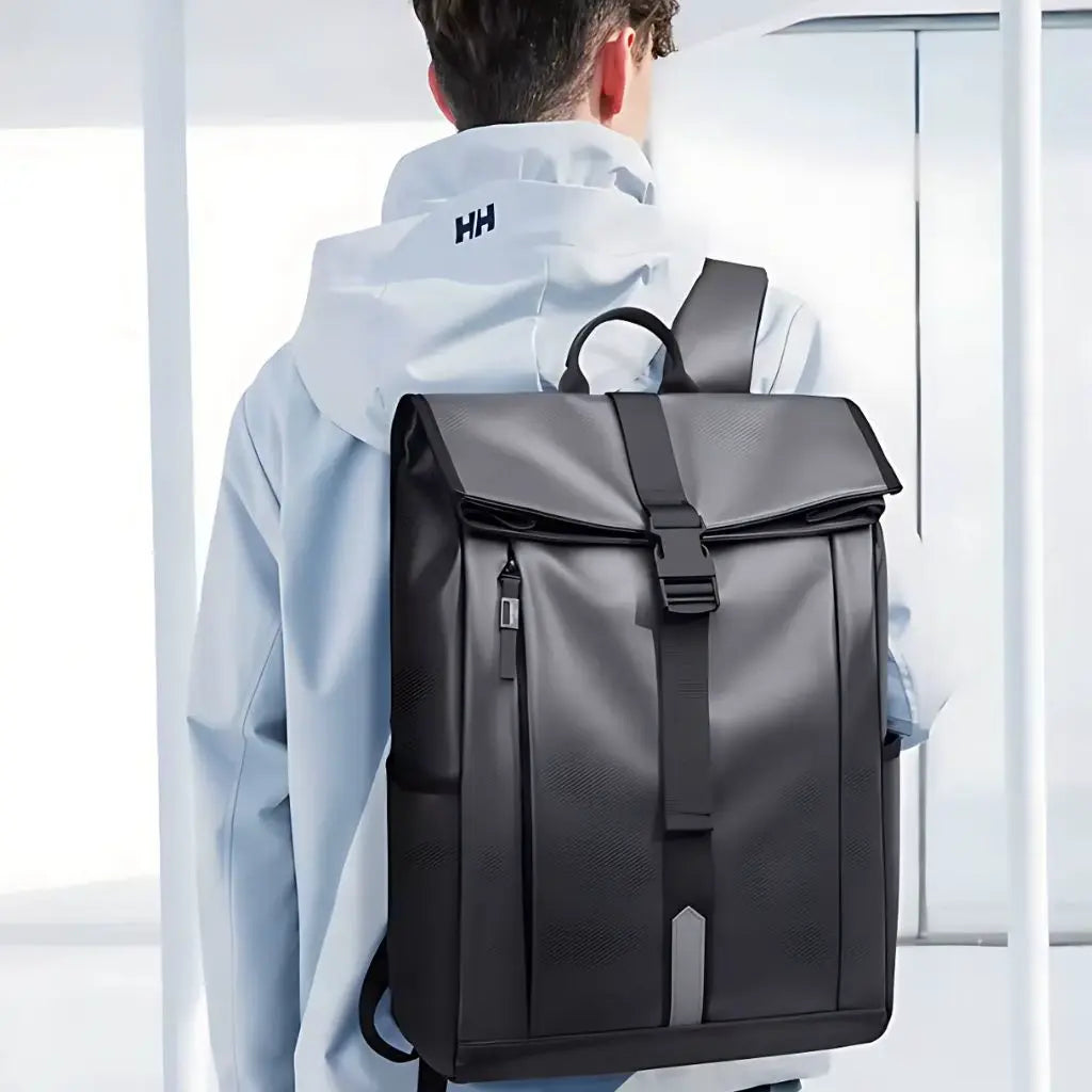 Achteraanzicht van een persoon die een waterdichte laptop rugzak 17.3 inch grijs draagt met een witte Helly Hansen jas. De rugzak toont het ergonomische ontwerp met brede schouderriemen en reflecterende strook voor veiligheid tijdens het fietsen.