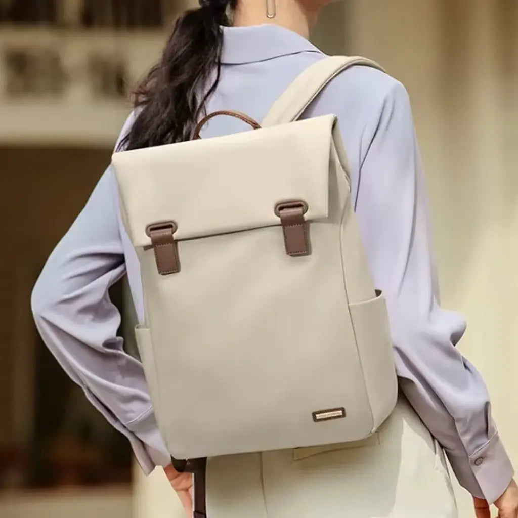Vrouw in lichtblauwe blouse die een beige waterdichte laptop rugzak dames 15.6 inch draagt, toont de stijlvolle pasvorm en het elegante contrast tussen de beige tas en formele zakelijke kleding.