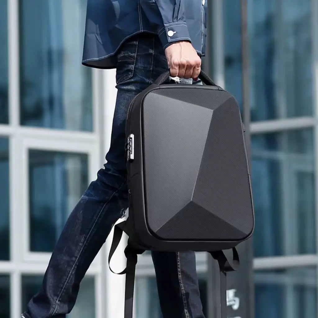 Man in casual zakelijke kleding die een zwarte waterdichte laptop rugzak heren 15.6 inch bij de bovenste handgreep vasthoudt, waarbij het strakke geometrische ontwerp en de duurzame constructie zichtbaar zijn.