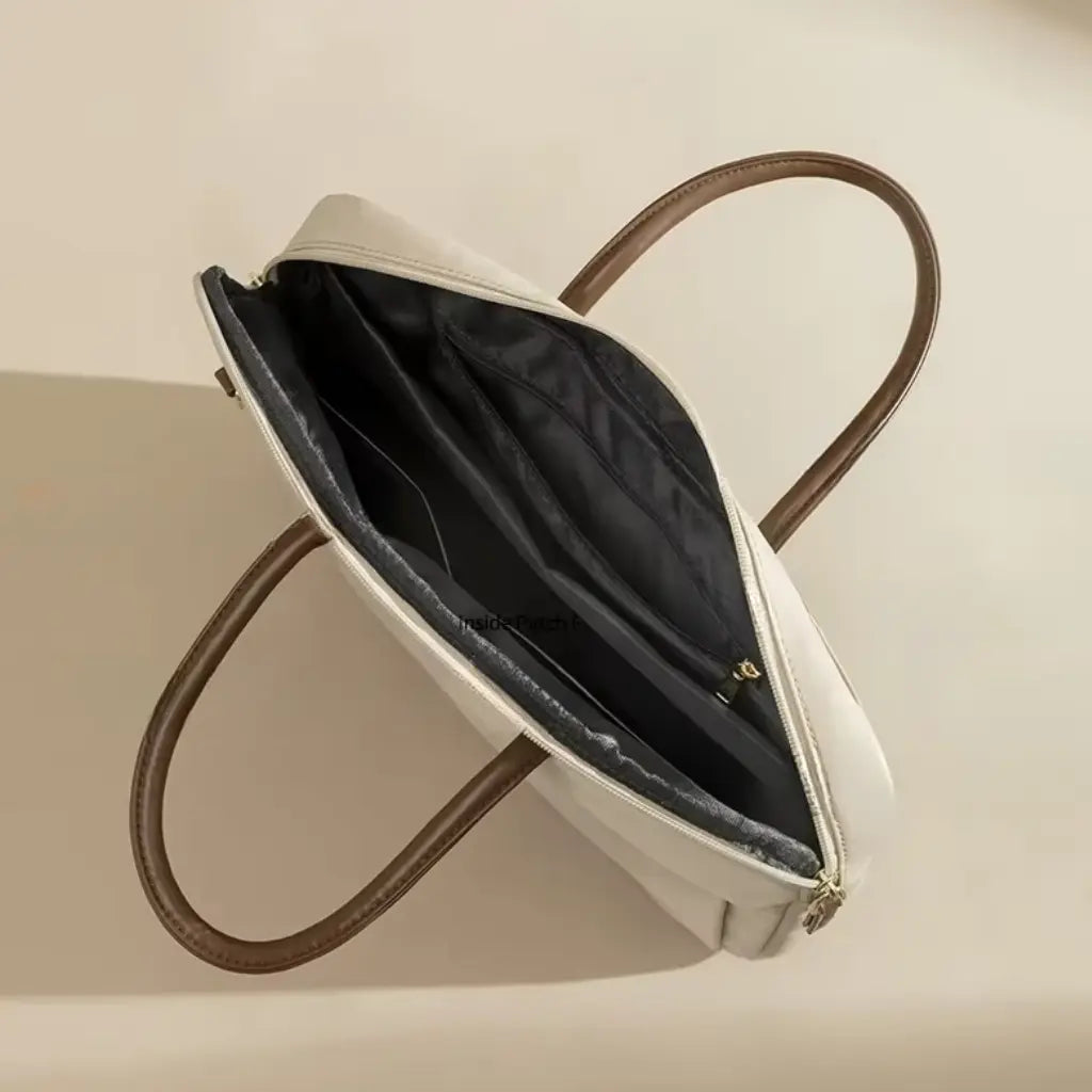 Open beige laptoptas voor dames met zwarte voering en meerdere vakken voor accessoires.
