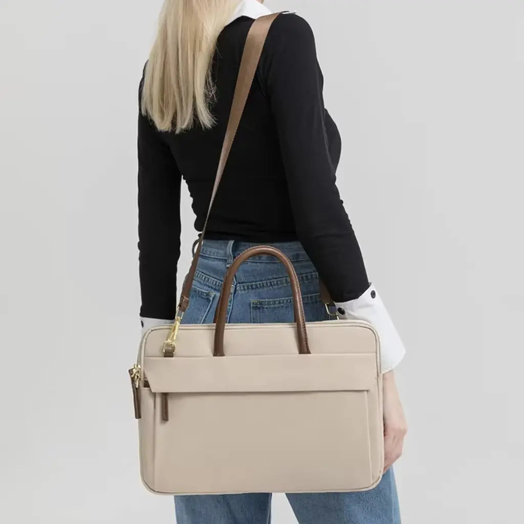 Achteraanzicht van een vrouw die een beige laptoptas voor dames draagt met een bruine schouderband.