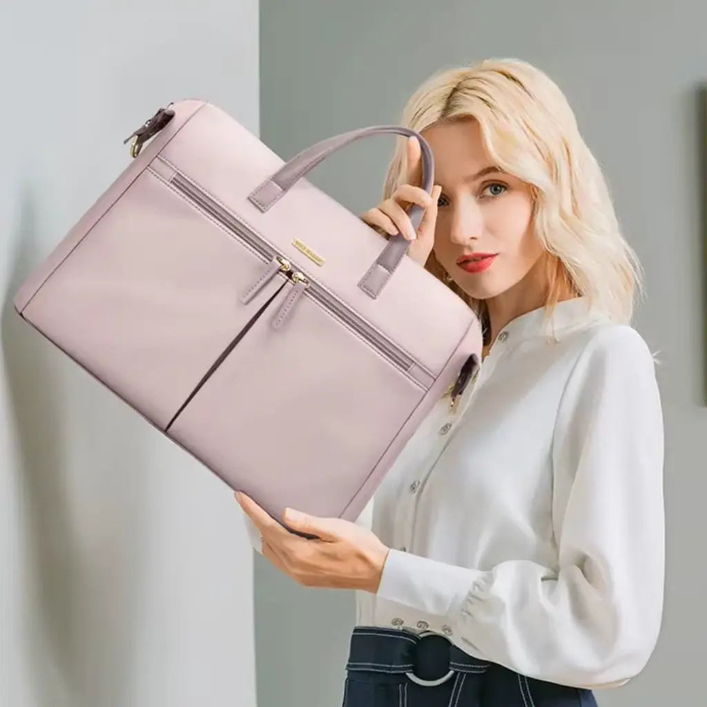 Model toont een roze laptoptas dames 15.6 inch in combinatie met een witte blouse en donkere broek. De laptoptas dames 15.6 inch roze voegt een subtiele kleuraccent toe aan zakelijke outfits en biedt elegantie met praktisch gebruiksgemak voor werkende vrouwen.