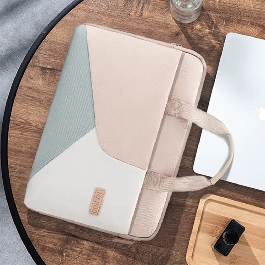Stijlvolle laptoptas dames op een houten tafel in moderne werkomgeving naast laptop en accessoires.